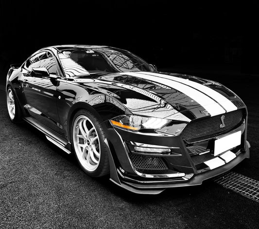 Side profile of a black 2018–2022 Ford Mustang with a Shelby GT500 front bumper conversion kit installed, featuring white racing stripes, aerodynamic styling, and aggressive front-end design.